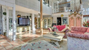 A spacious living area with a television, seating, and a balcony.