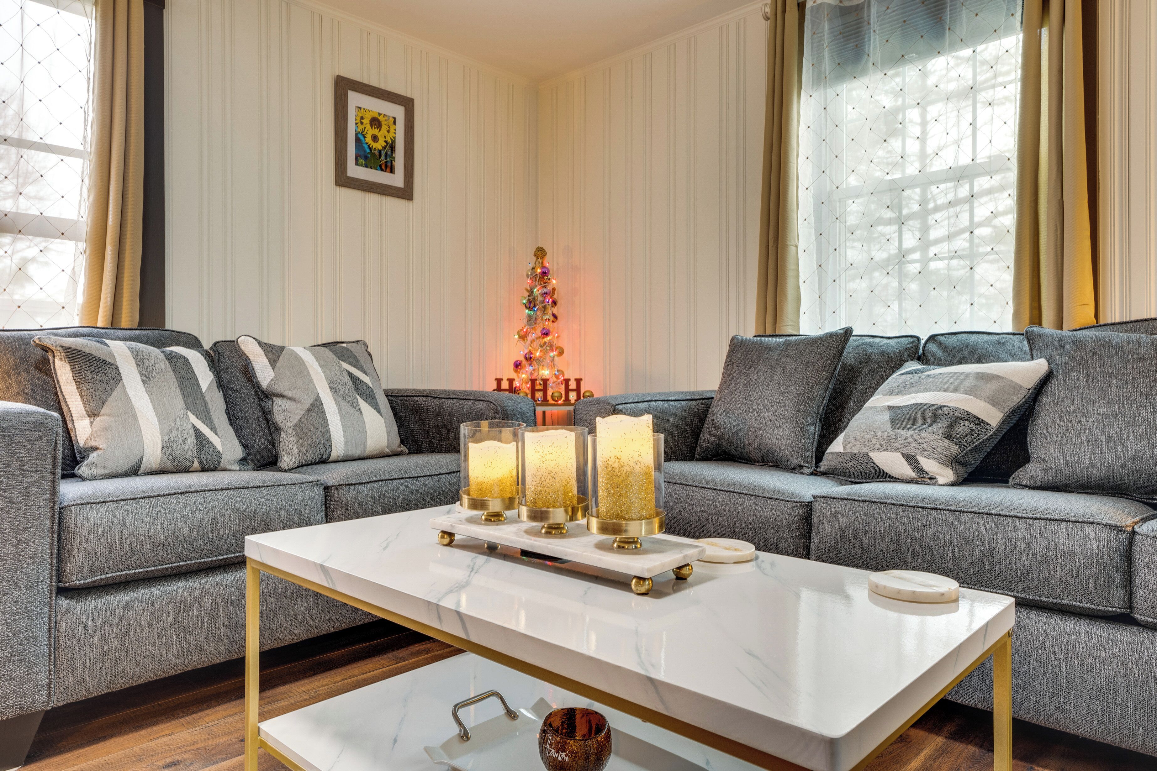 A modern living room with a grey sofa, a white coffee table, and a decorative Christmas tree.