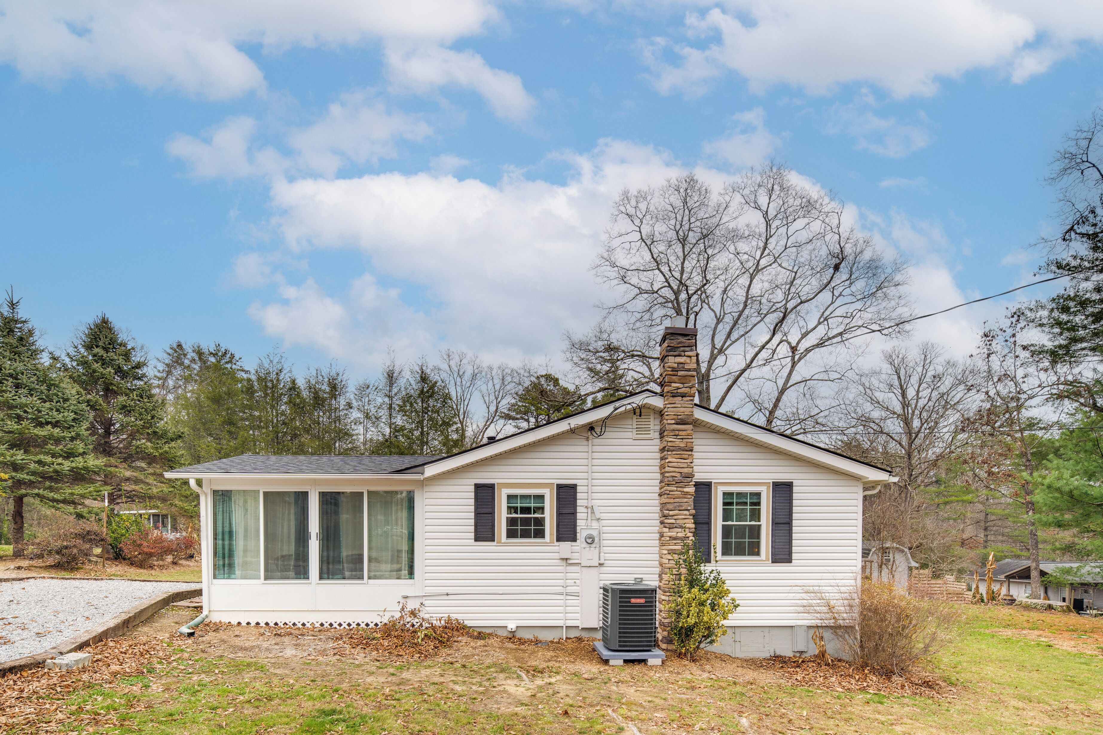 A single-story house with a chimney, large windows, and an air conditioning unit.