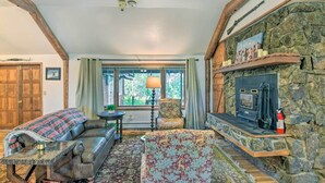 A cozy living room with a stone fireplace, leather sofa, and a large window with curtains. - 'moose Park Lodge' Charming Walden Retreat! (Walden)