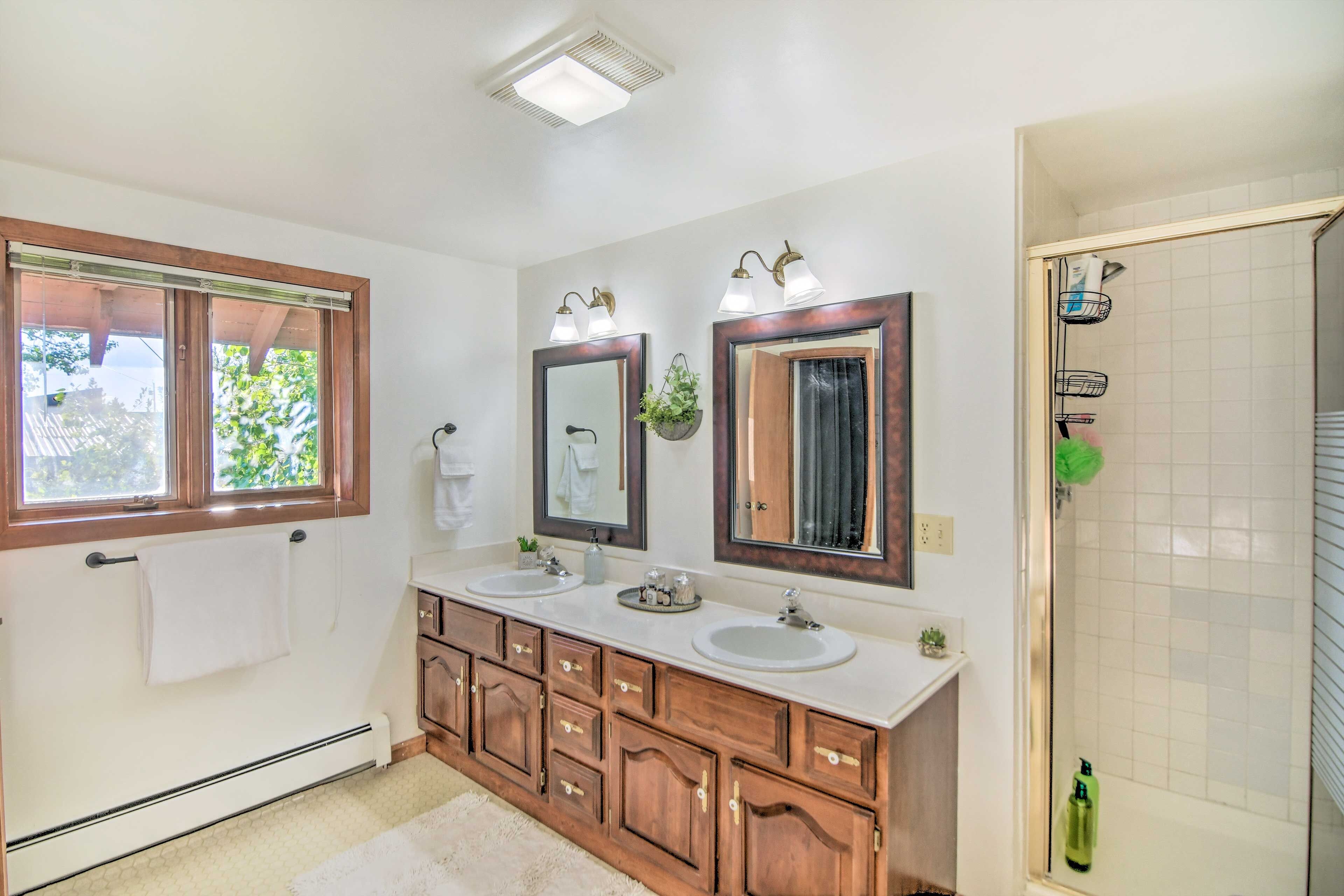 Une salle de bain avec deux lavabos, des meubles en bois, un grand miroir et un espace douche.