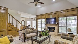 A spacious living room with a fireplace, a large TV, and a staircase leading to another level. - Spacious Houston Getaway ~ 23 Mi to Downtown! (Houston)