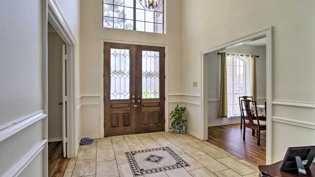 A spacious foyer with a large wooden double door, a patterned rug, and a chandelier. - Spacious Houston Getaway ~ 23 Mi to Downtown! (Houston)
