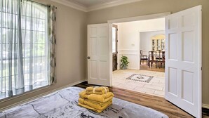 A room with a marble-patterned rug, a stack of yellow towels, and a view into a dining area with a chandelier and a plant. - Spacious Houston Getaway ~ 23 Mi to Downtown! (Houston)