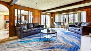 A spacious living room with two leather sofas, a coffee table, and a large blue patterned rug. - Spacious Buffalo Brick Home w/ Backyard! (Buffalo)