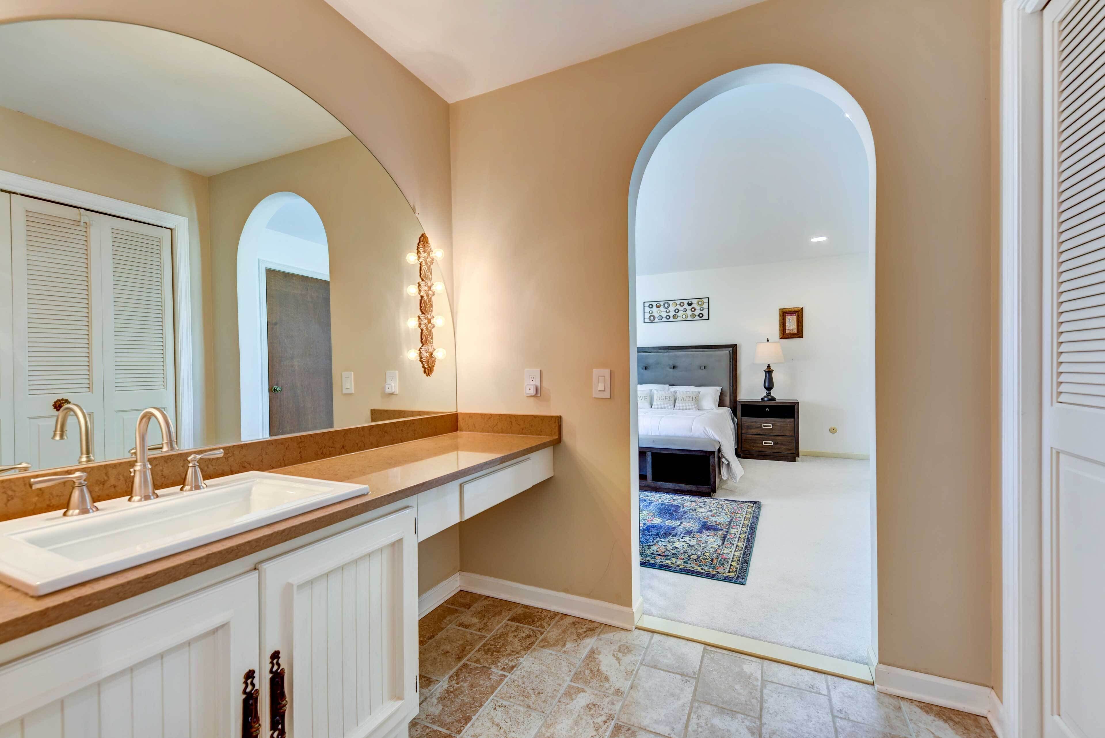 Une salle de bain avec un grand miroir, un meuble-lavabo et un évier.