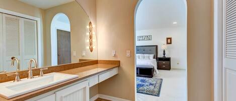 A bathroom with a large mirror, vanity, and a sink.