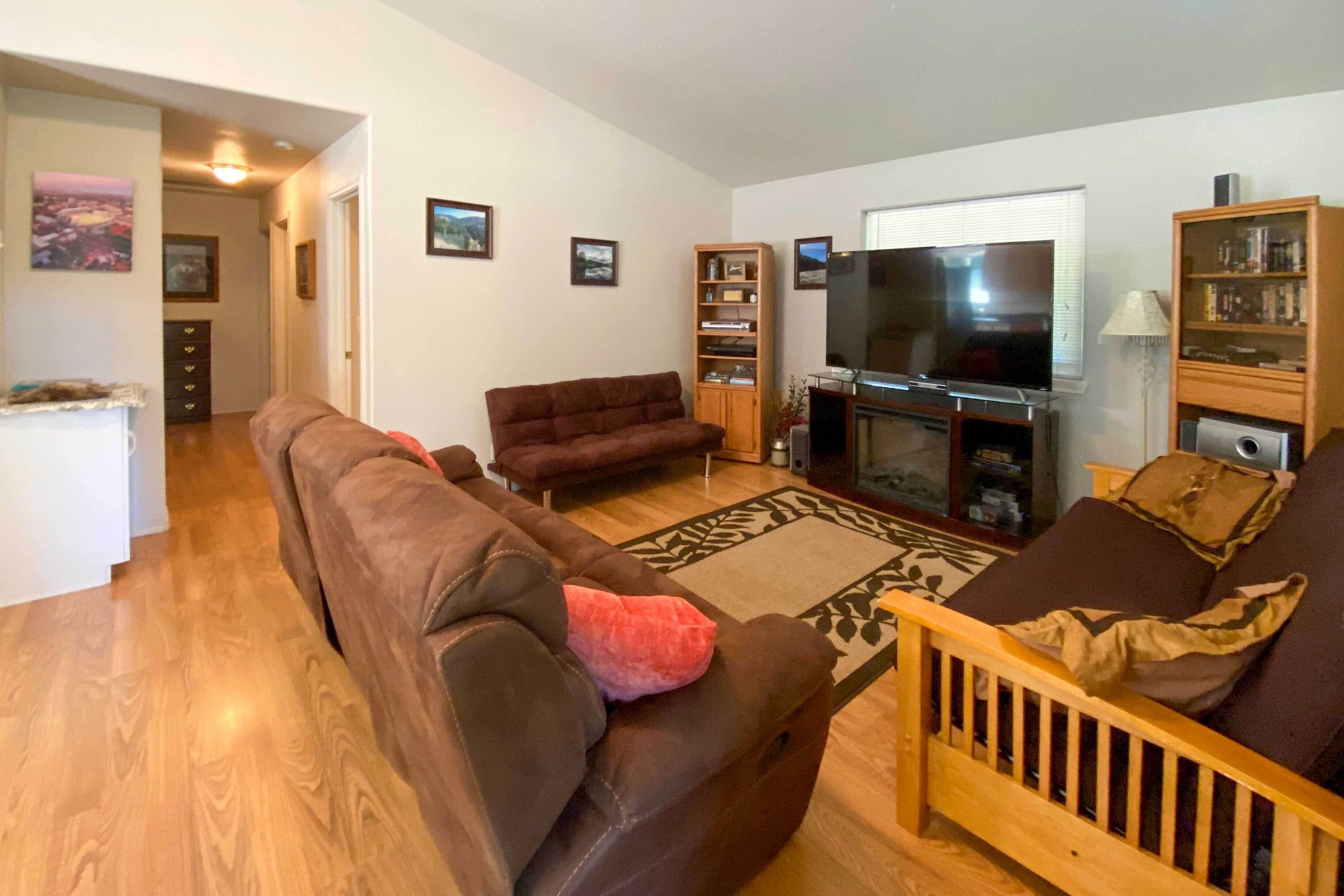 A living room with a brown sofa, a wooden coffee table, a television, and a bookshelf.