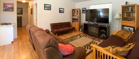 A living room with a brown sofa, a wooden coffee table, a television, and a bookshelf.