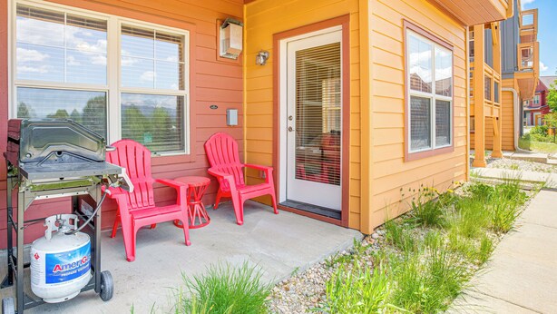 A house with a porch, red chairs, a propane tank, and a door with a window. - Condo Near Winter Park Resort + Steps From Shuttle (Fraser)