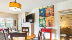 A dining area with a wooden table and chairs, a red sideboard, and a large bear-themed artwork on the wall. - Condo Near Winter Park Resort + Steps From Shuttle (Fraser)