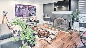 A modern living room with a fireplace, leather sofa, and a large abstract painting.