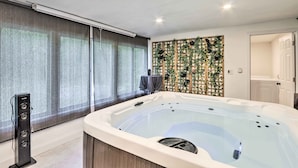 A modern bathroom with a large bathtub, a shower area, and a decorative wall with greenery.