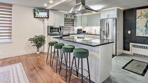 A modern kitchen with white cabinets, stainless steel appliances, and a central island with bar stools.