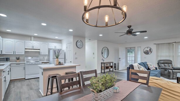 A modern kitchen with white cabinets, a central island, and a dining area with a table and chairs. - Pet-friendly PNW Home, 1 Mi to Rockaway Beach (Rockaway Beach)