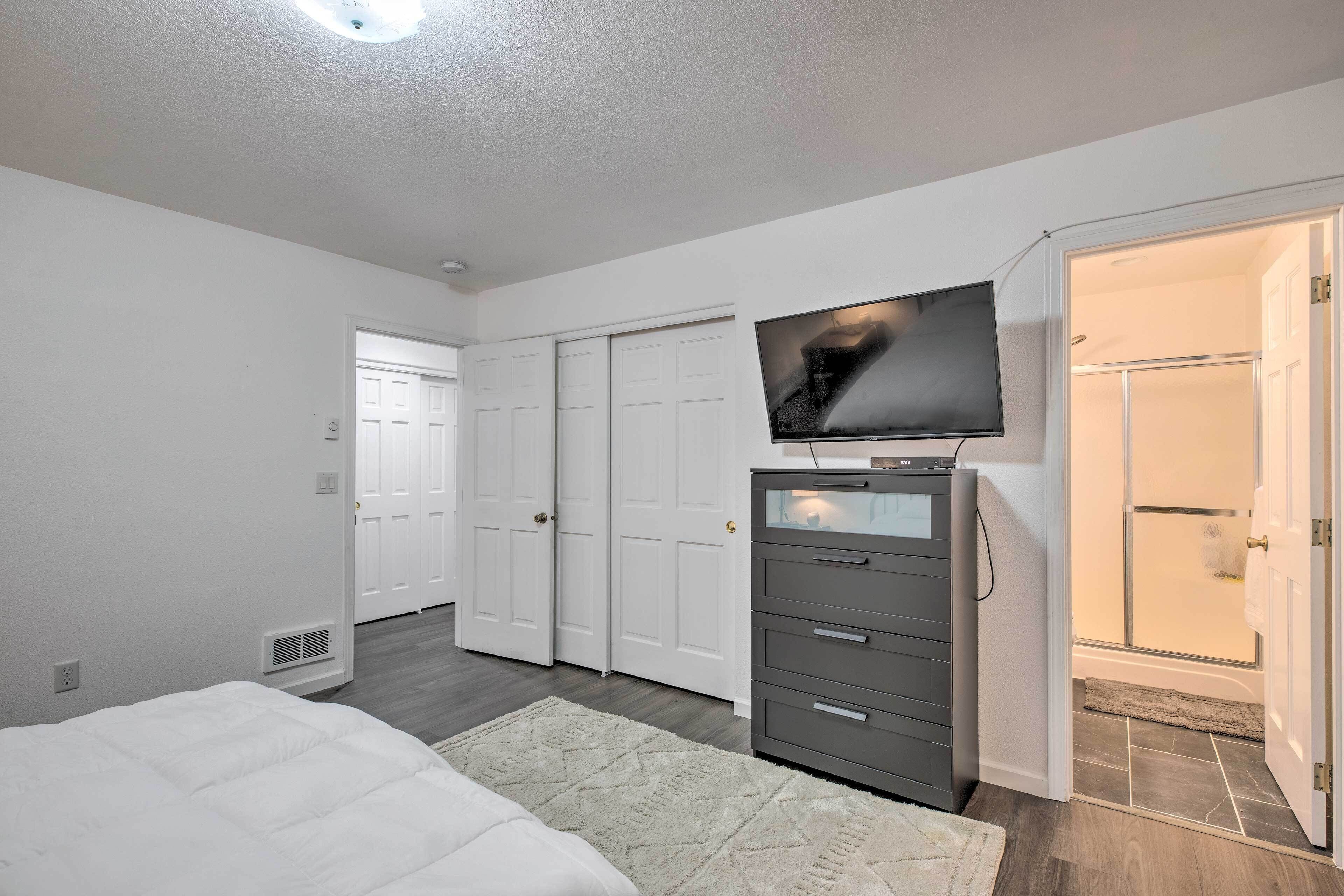A bedroom with a bed, a dresser, a television, and a walk-in closet.