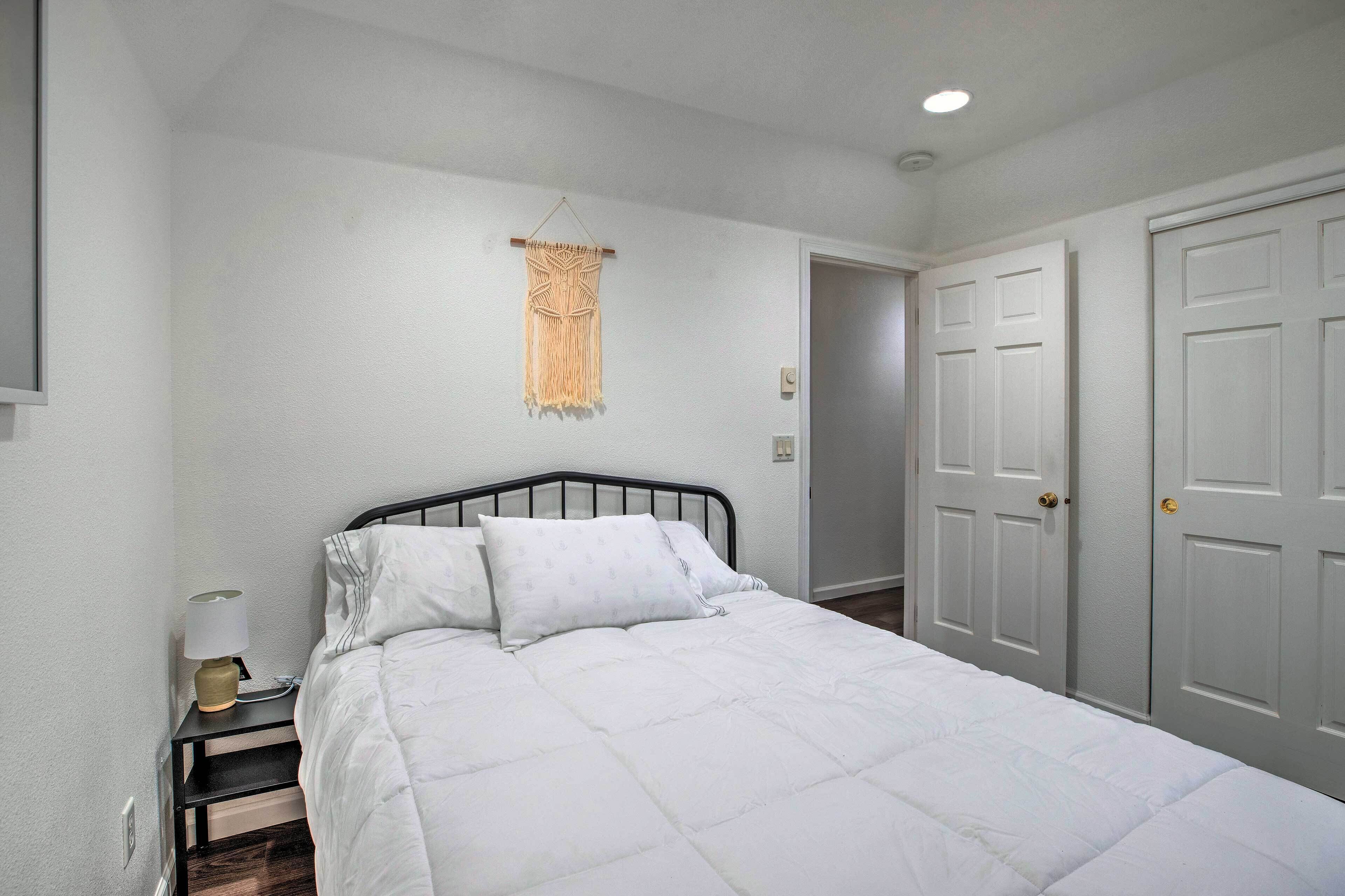 A neatly arranged bedroom with a bed, bedside table, and a hanging macrame piece.