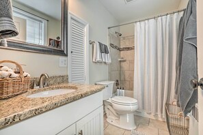 A bathroom with a granite countertop sink, a toilet, and a shower with a glass door.