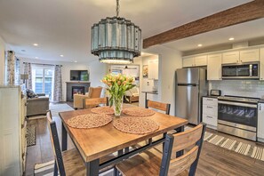A modern kitchen with stainless steel appliances, a wooden dining table with placemats, and a hanging light fixture. - Updated Port Orchard Home, Walk to Waterfront (Port Orchard)
