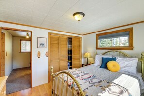 Een slaapkamer met een bed, een raam, een plafondlamp en een houten deur.