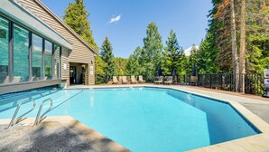 A swimming pool with lounge chairs and a building with large windows.