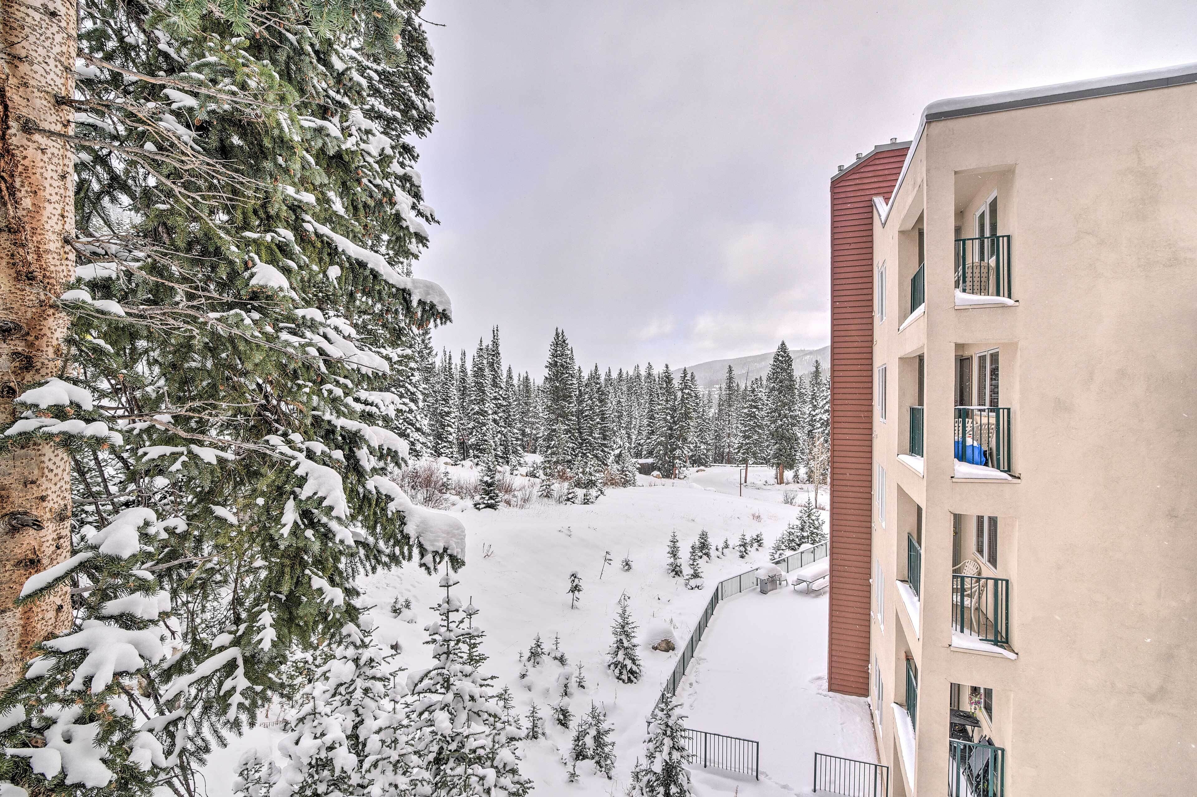 A snow-covered landscape with a building featuring balconies and a view of a forest.