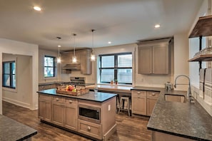 A modern kitchen with wooden cabinets, a central island, stainless steel appliances, and pendant lighting. - Updated Downtown Red Bank Home 5 Mi to Beach! (Red Bank)