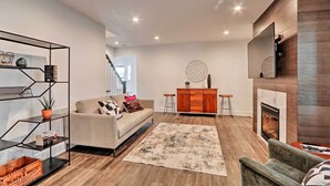 A modern living room with a sofa, a coffee table, a fireplace, and a bookshelf. - Updated Downtown Red Bank Home 5 Mi to Beach! (Red Bank)
