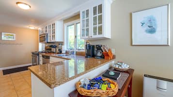 A modern kitchen with granite countertops, white cabinetry, and a large island.