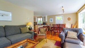 Ein Wohnzimmer mit einem grauen Sofa, einem braunen Ledersofa und einem Essbereich mit Holzsesseln und einem Tisch.