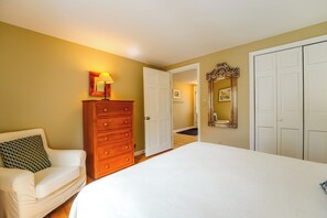 A bedroom with a bed, a dresser, a chair, and a door leading to another room.