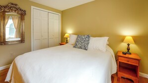 Een slaapkamer met een bed, twee bedlampen, een spiegel en een kledingkast.