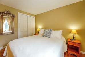 Une chambre à coucher avec un lit, deux lampes de chevet, un miroir et une armoire.