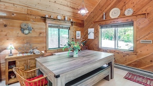 A wooden cabin interior with a dining table, chairs, a vase with flowers, and a hanging light fixture. - Mars Hill Cabin w/ Pool Table ~ 2 Mi to Wolf Ridge (Mars Hill)