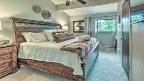 A bedroom with a wooden bed, a ceiling fan, and a view of the outdoors through a window. - Rustic Ruidoso Retreat Near Shops & Mountains! (Ruidoso)