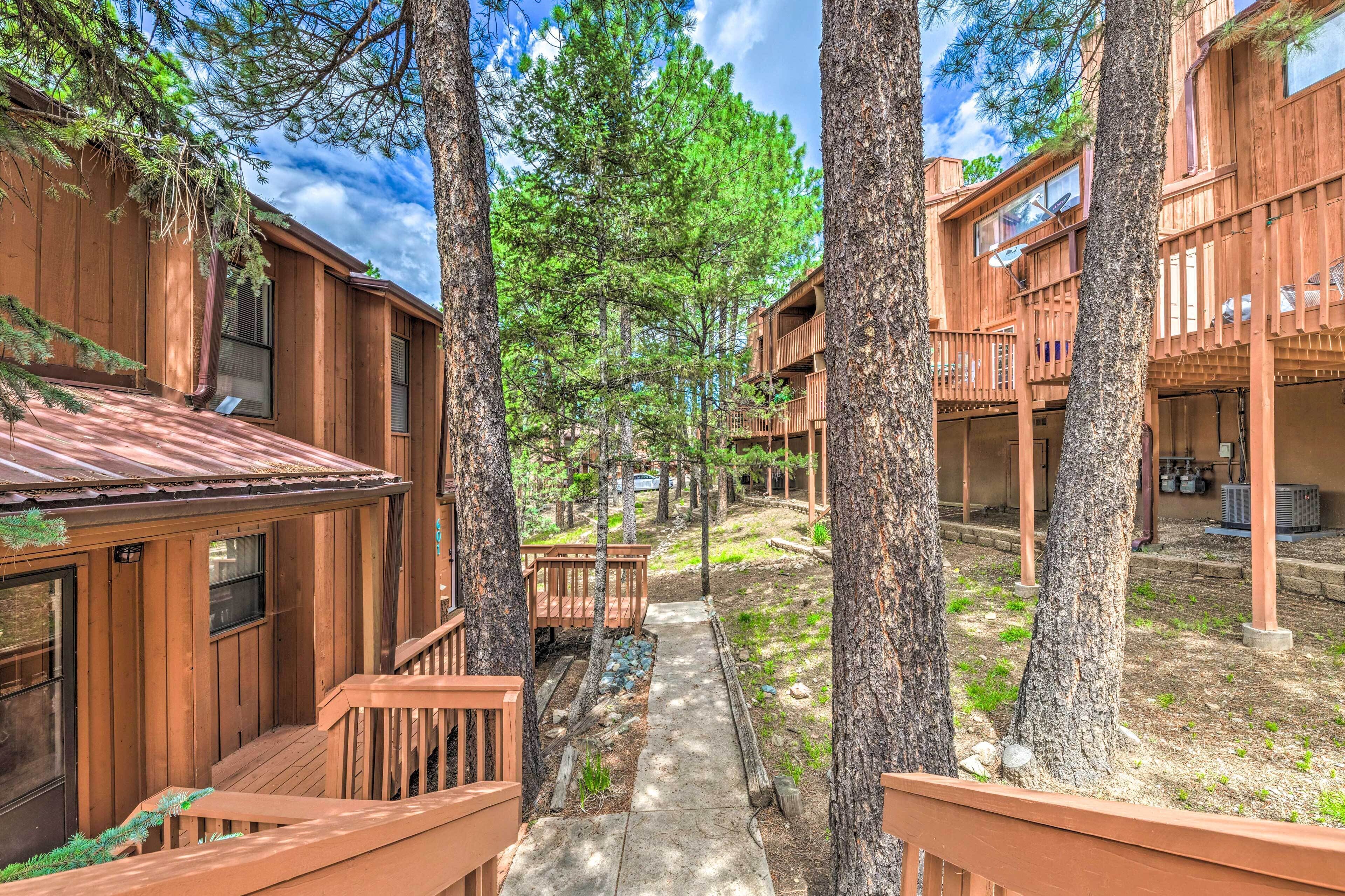 A wooden cabin-style building with multiple balconies and a central pathway surrounded by trees.