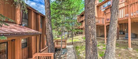 A wooden cabin-style building with multiple balconies and a central pathway surrounded by trees.