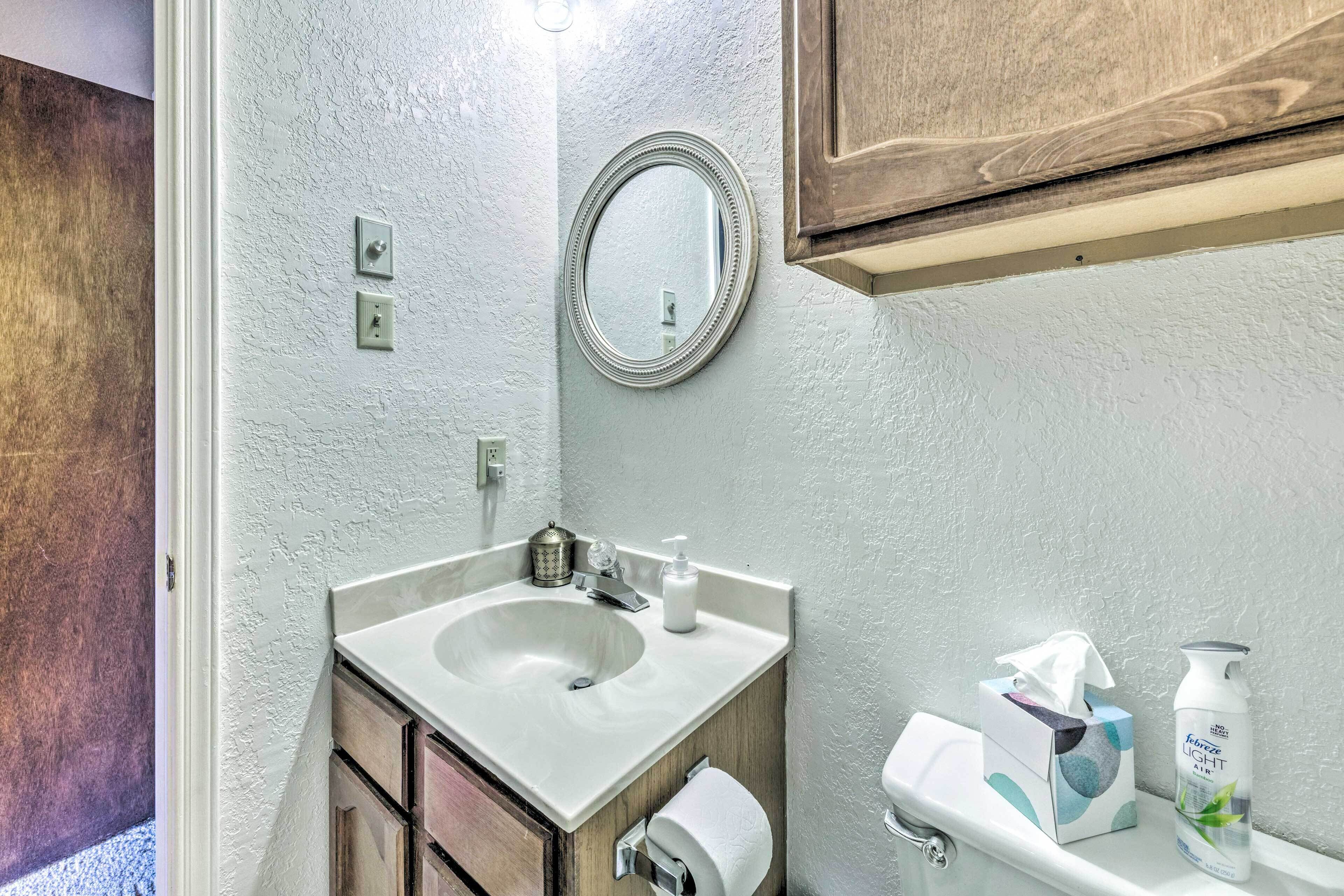 A bathroom with a white sink, a mirror, a toilet, and a cabinet.