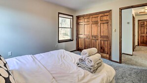 Un dormitorio con cama, ventana, armario y puerta.