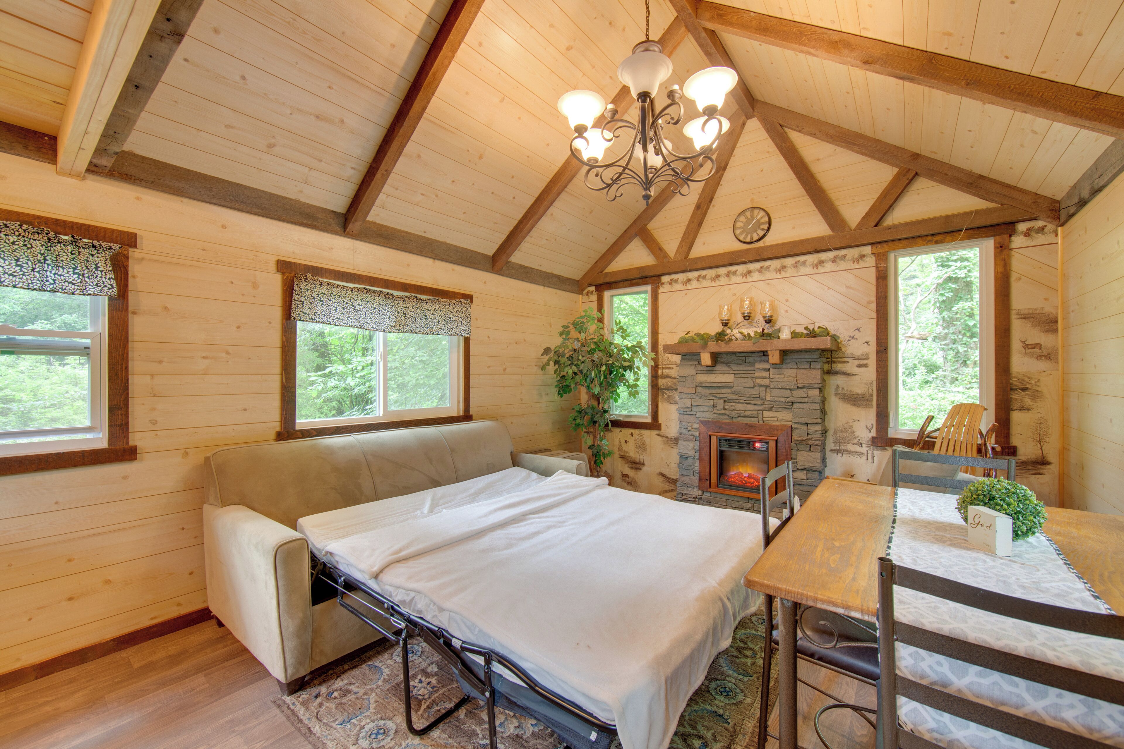 A cozy room with a bed, a sofa, a fireplace, and a dining table.