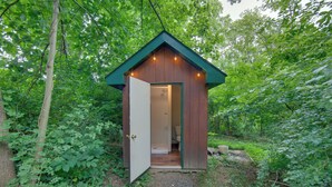 Un piccolo chalet di legno con la porta aperta, immerso nel verde.