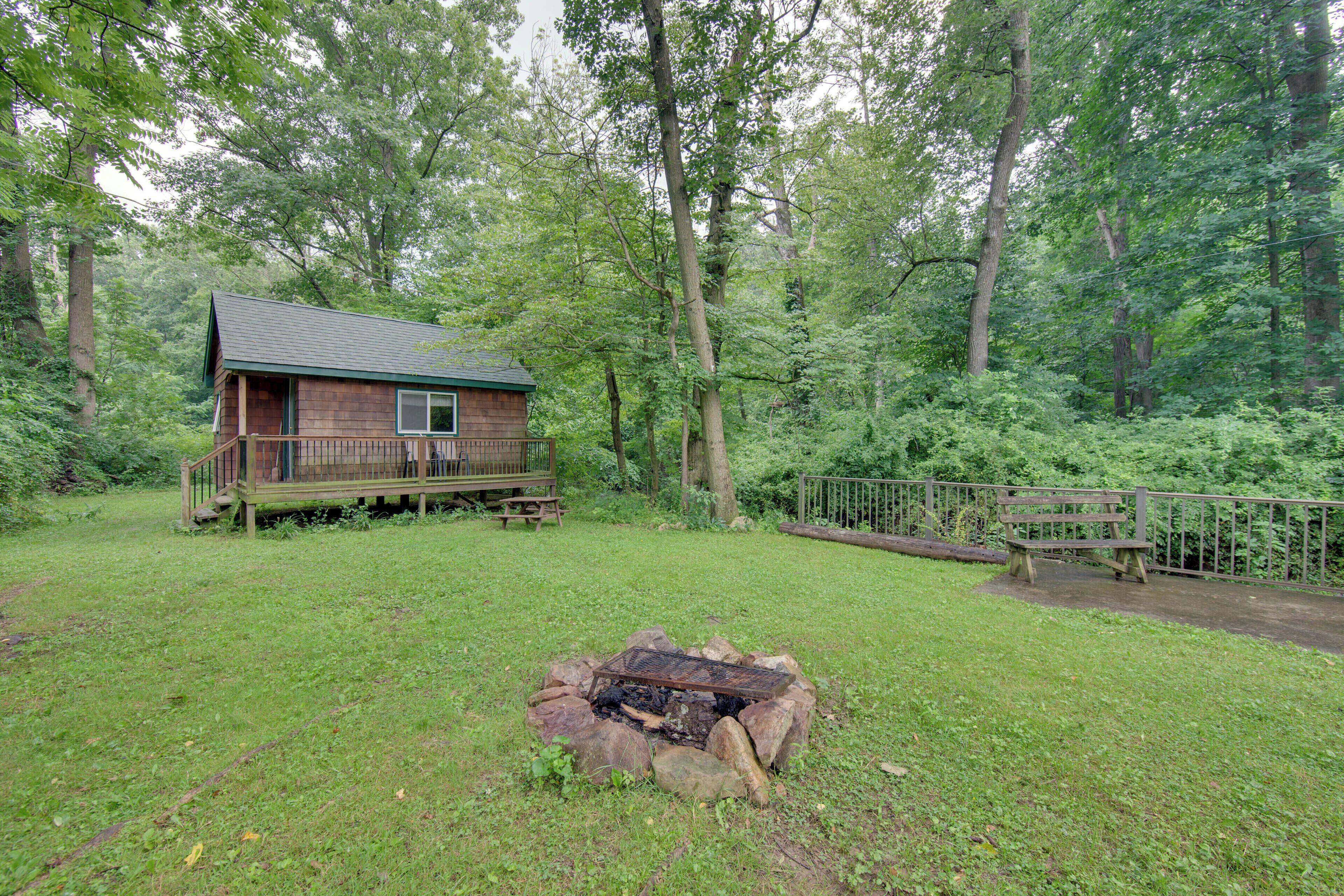 A cabin with a deck, surrounded by a forest.