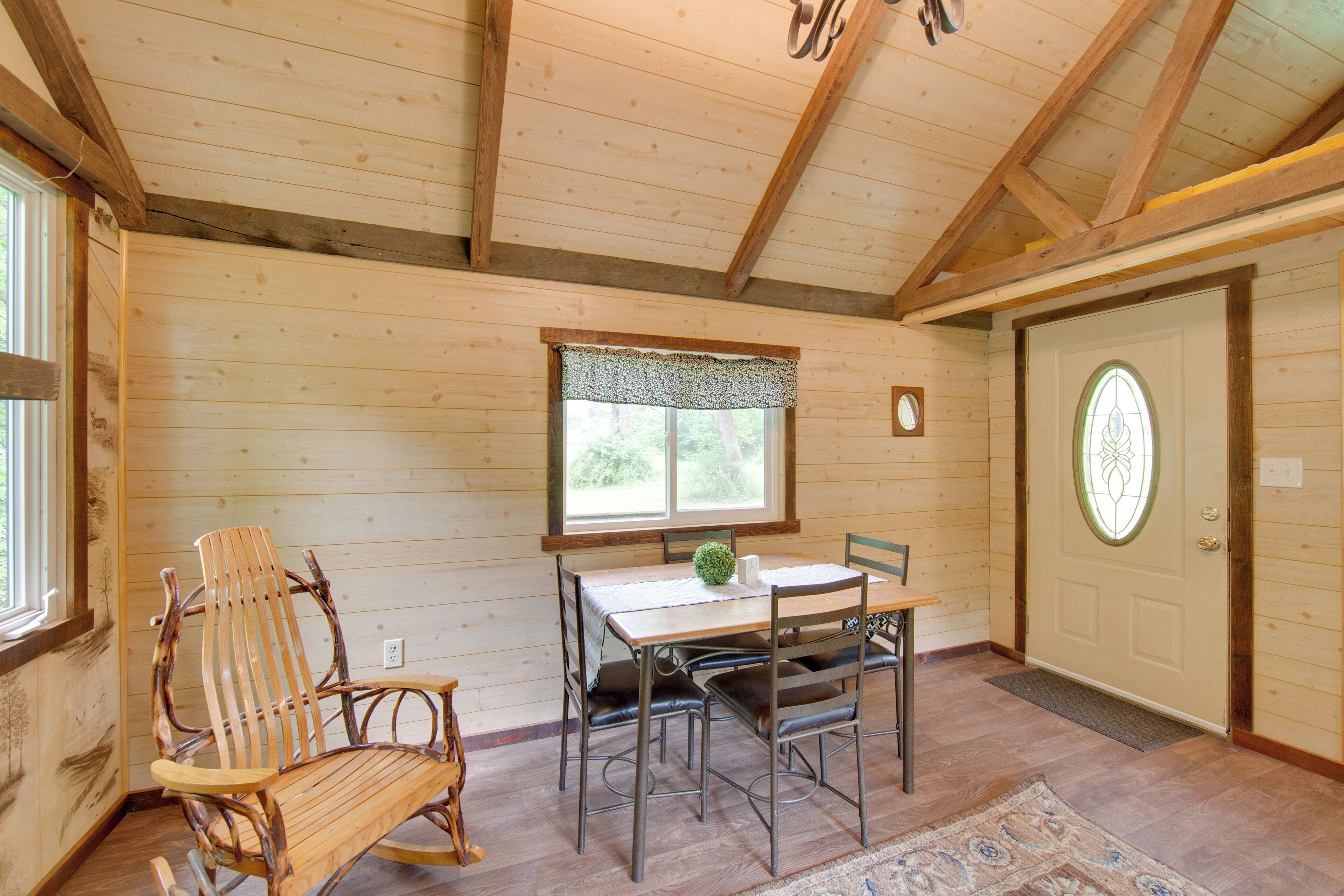 A wooden interior with a dining table, chairs, and a rocking chair.