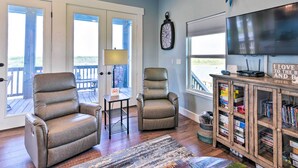 A living room with two leather recliners, a wooden cabinet with books, a mounted fish decoration, and a large TV. - Waterfront Sargent House w/ Sparkling Pool! (Bay City)