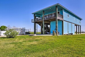 A two-story building with a balcony on the upper floor, situated on a grassy area with a clear sky.