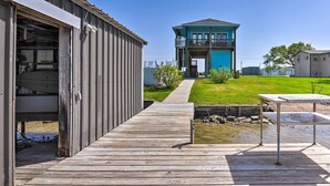 A wooden dock leading to a house with a blue exterior and a balcony. - Waterfront Sargent House w/ Sparkling Pool! (Bay City)