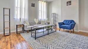 Una sala de estar con un sofá gris, un sillón azul, una mesa de centro y un tapete estampado.