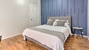 Un dormitorio con una cama, una mesita de noche, una puerta y una pared con líneas verticales.