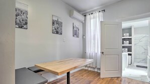 Una habitación con una mesa de madera, un banco y una puerta que da a un baño.
