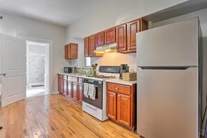 Una cocina con armarios de madera, un refrigerador de acero inoxidable, una estufa y un microondas.